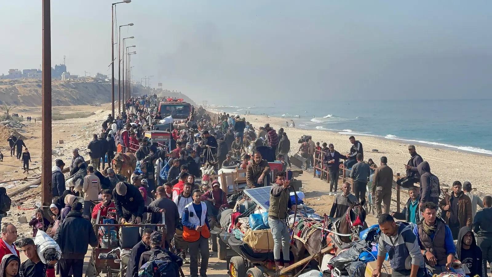 Crowds of displaced Palestinians walking north along the coastal road in Gaza